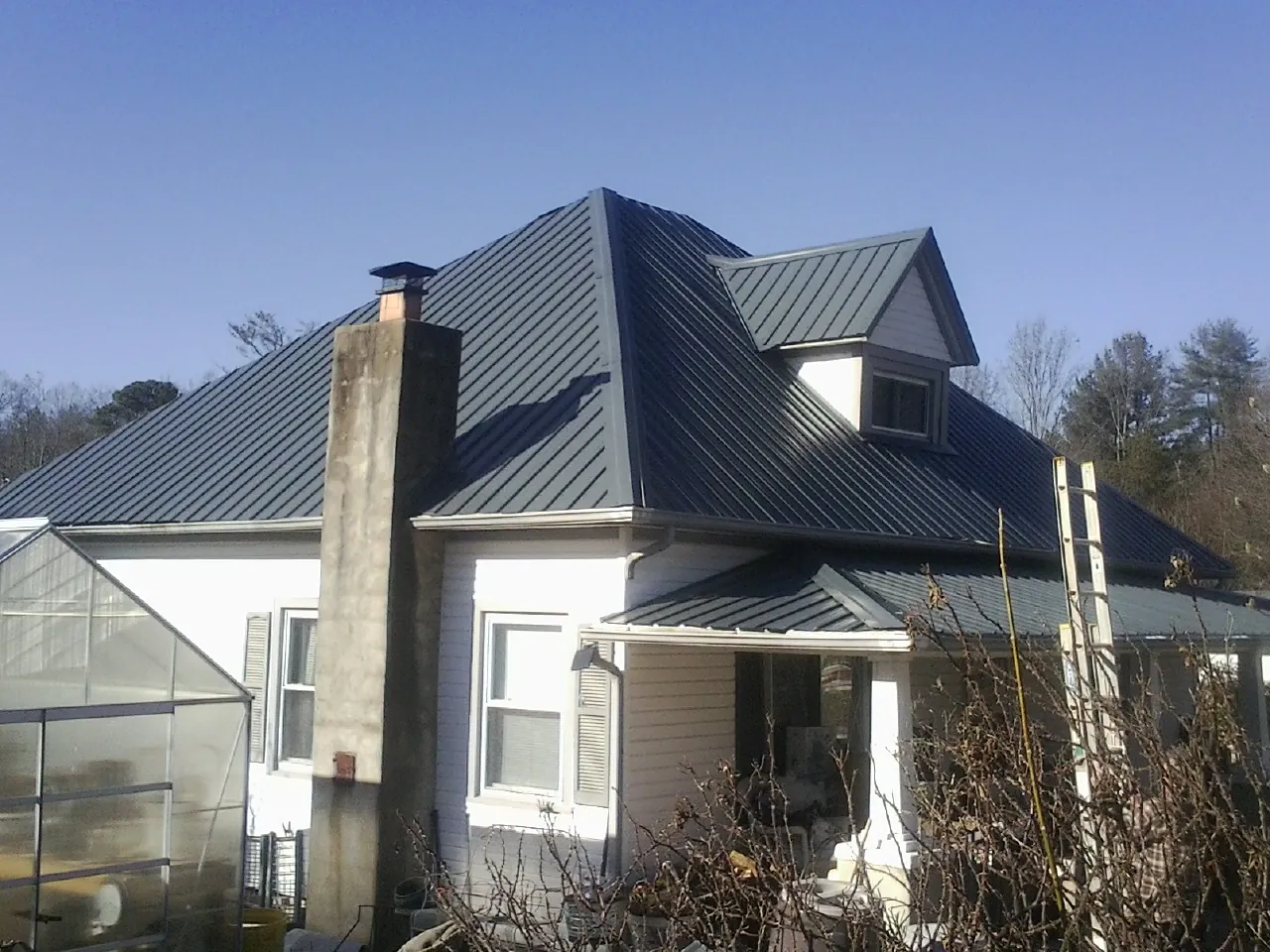 Dark blue standing seam metal roof on a white farmhouse with dormer — Slate & Tile Roof Repair by Roofing Brothers in Hope Valley