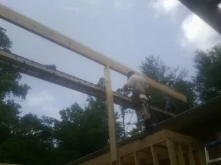 Carpenter setting a ridge beam over a new addition frame — Ice Dam Removal by Roofing Brothers in Hope Valley