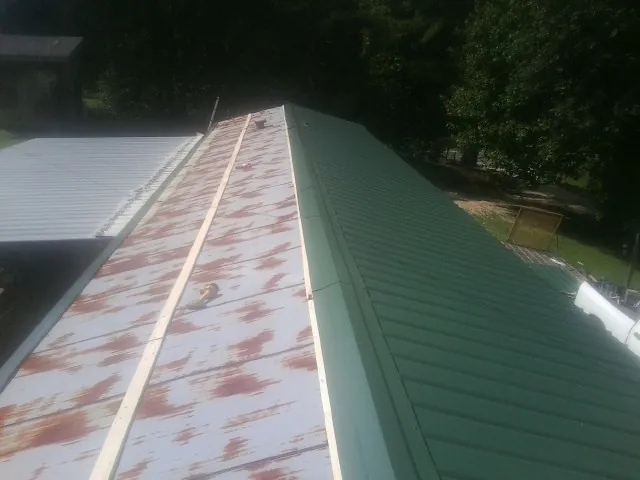 Old rusted panels beside newly installed green metal roofing — Wind Damage Roof Repair by Roofing Brothers in Hope Valley