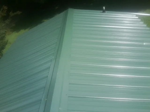 New green metal panels meeting at the ridge of a roof — Flat Roof Repair work by our crew in Hope Valley
