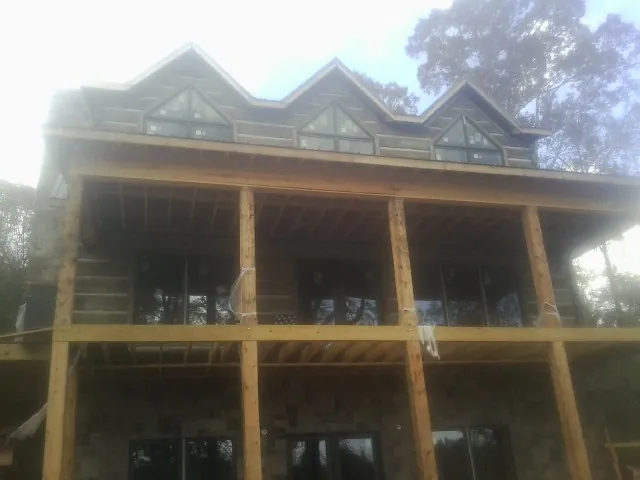 Dormers and porch framing on a large log home under construction — Roof Coating work by our crew in Hope Valley