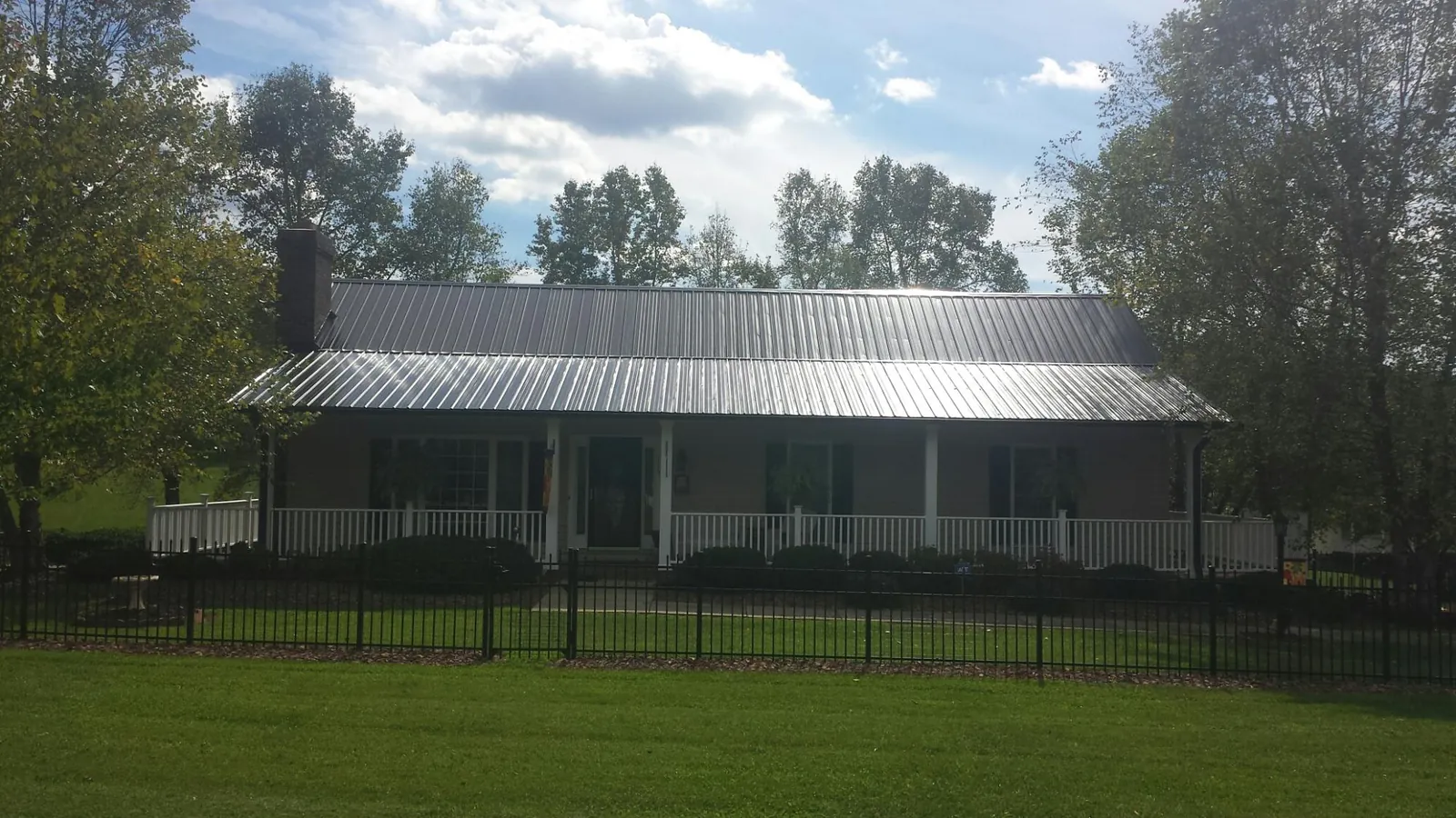 Gray metal roof on a brick ranch with a full width front porch — Gutter Guard Installation work by our crew in Hope Valley