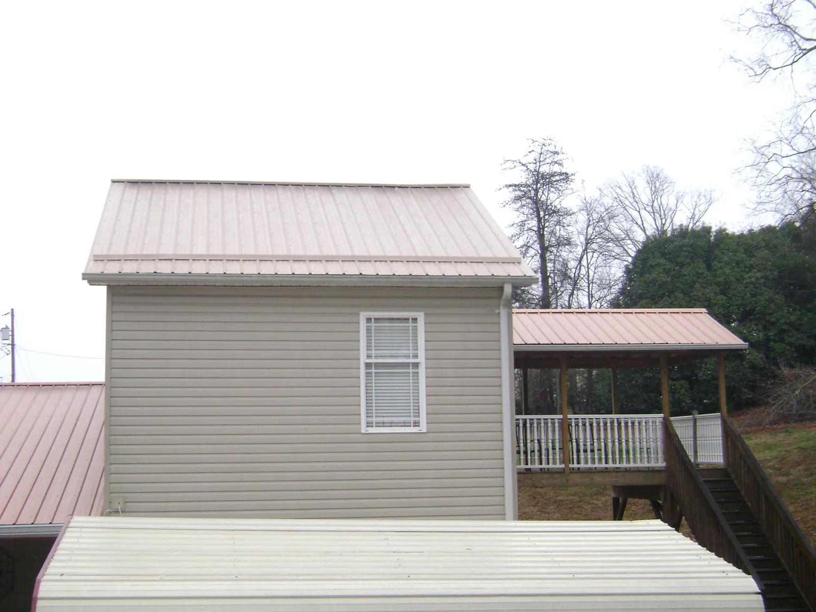 Tan metal roofs on a two story addition and attached porch, from a Roof Replacement job in Hope Valley