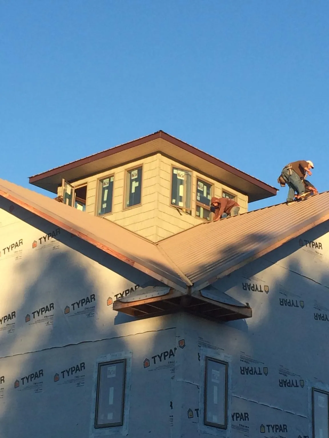 Roofers working around a rooftop cupola on a new metal roof at sunset — Roof Waterproofing in Hope Valley by Roofing Brothers